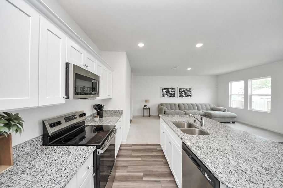 Sleek kitchen with granite countertops and stainless steel appliances flows seamlessly into an open, bright living area, perfect for entertaining.