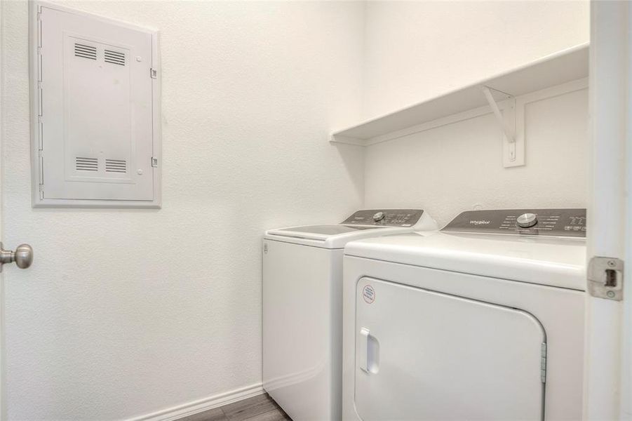 Laundry area with washing machine and clothes dryer, a textured wall, and electric panel Laundry area with washing machine and clothes dryer, a textured wall, and electric panel