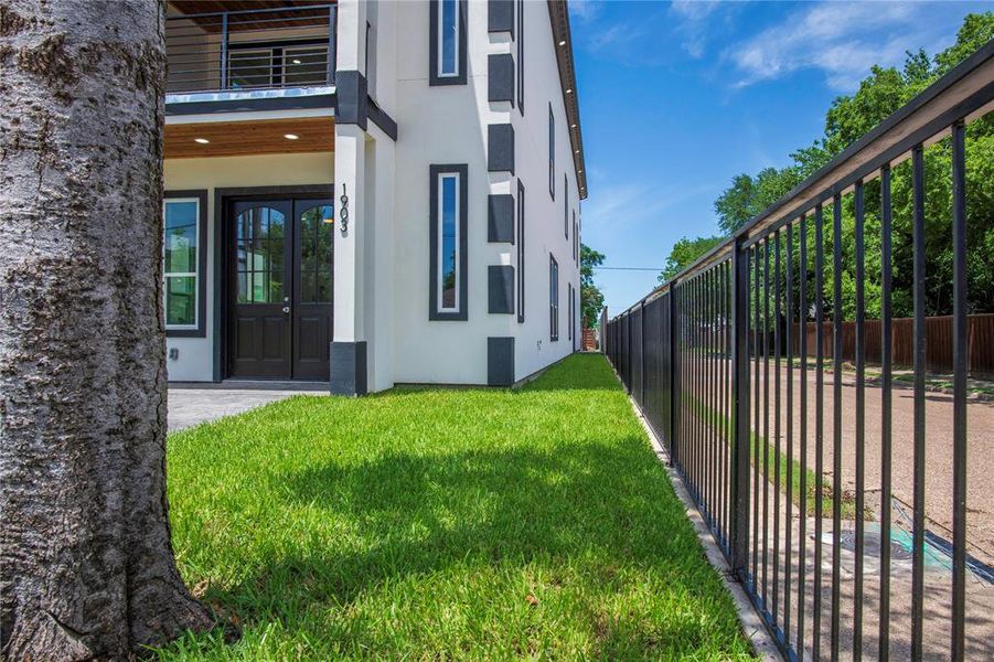 View of exterior entry with a yard, french doors, and a balcony