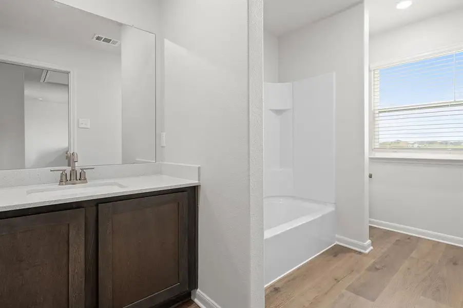 Full bathroom with vanity, shower / bath combination, and light wood-type flooring