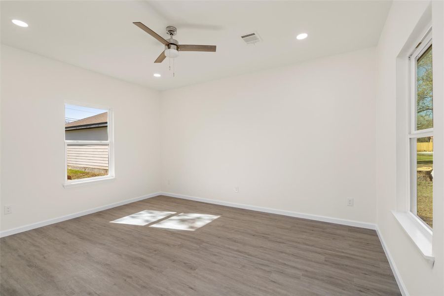 Generously sized primary bedroom with ceiling fan and serene backyard views.