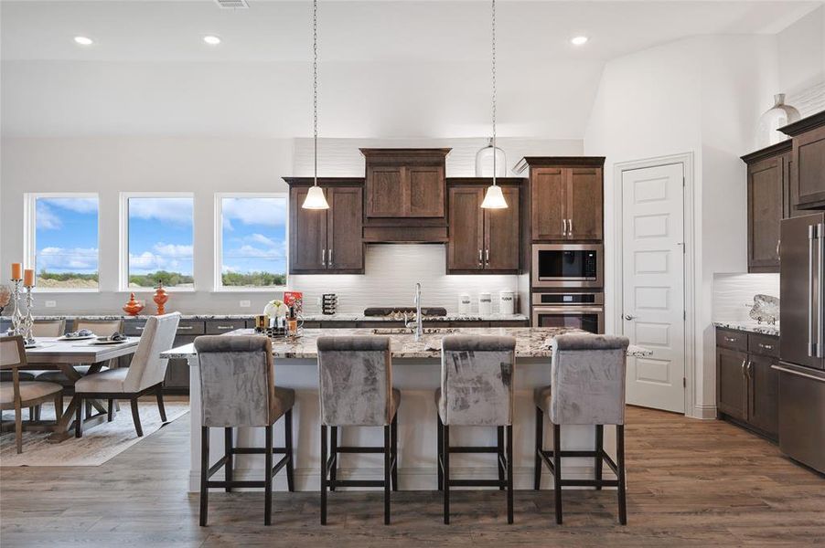 Kitchen featuring dark hardwood / wood-style floors, tasteful backsplash, an island with sink, stainless steel appliances, and light stone counters