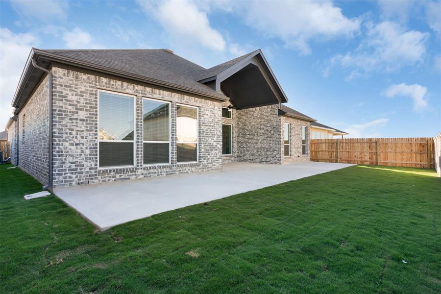 Rear view of property featuring a fenced backyard, brick siding, a patio area, and a shingled roof