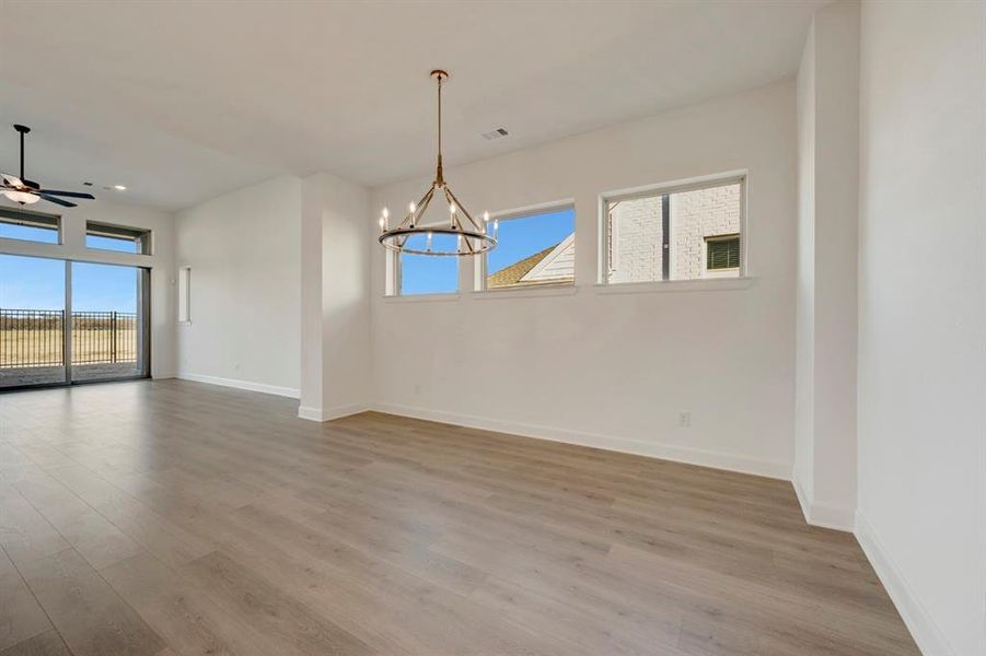 Empty room featuring ceiling fan, light wood finished floors, healthy amount of natural light, and hanging lights Empty room featuring ceiling fan, light wood finished floors, healthy amount of natural light, and hanging lights