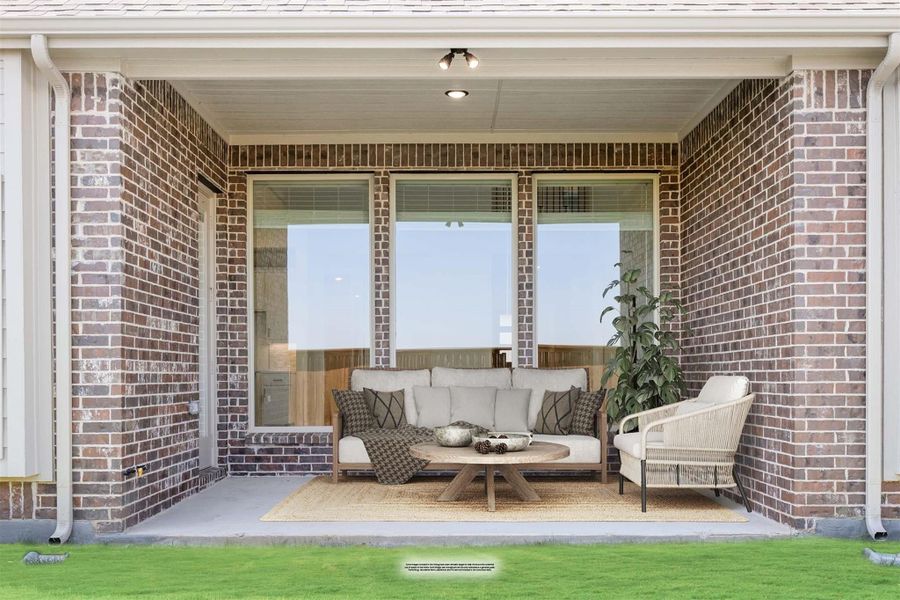 Covered brick patio with outdoor sofa, chair, and coffee table on a jute rug Covered brick patio with outdoor sofa, chair, and coffee table on a jute rug