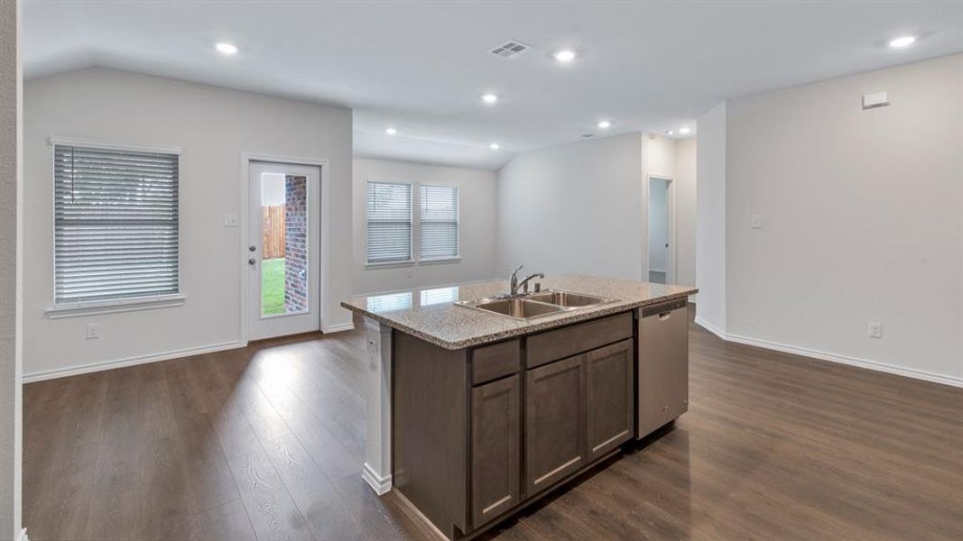 Kitchen featuring a center island with sink, dark wood finish cabinetry, stainless steel dishwasher, dark wood finished floors, and recessed lighting