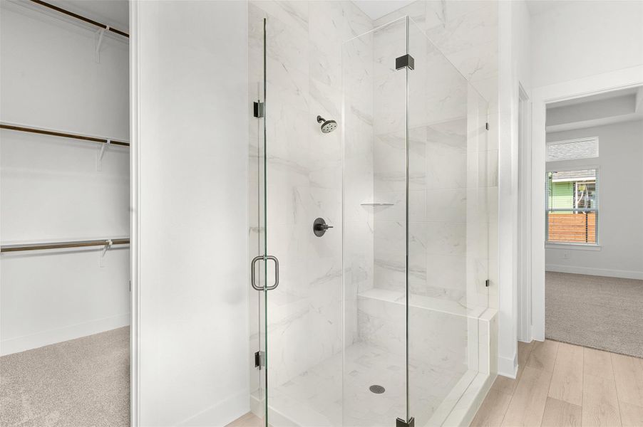 Bathroom featuring a marble finish shower and a spacious closet