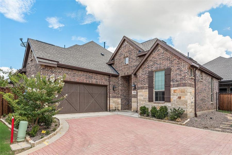 View of front of house with brick siding, roof with shingles, an attached garage, and decorative driveway View of front of house with brick siding, roof with shingles, an attached garage, and decorative driveway