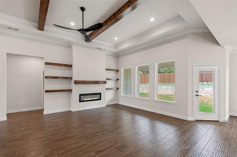 Unfurnished living room featuring beamed ceiling, crown molding, and dark wood-type flooring