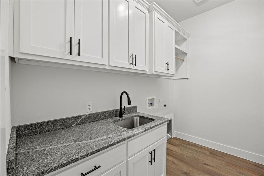 Laundry area featuring light wood-style flooring, cabinet space, hookup for a washing machine, and hookup for an electric dryer