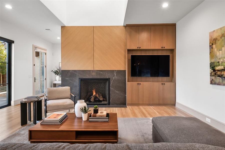 Living room with light wood-style flooring, recessed lighting, and a lit fireplace