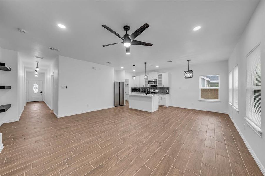 Unfurnished living room with sink, ceiling fan, and light hardwood / wood-style floors