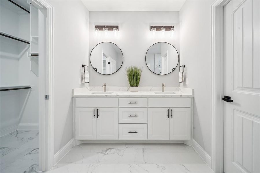 Dual vanity with white cabinetry, white countertop, and round black-framed mirrors