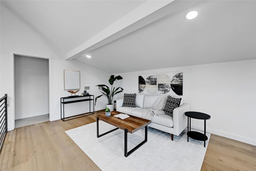 Living room featuring light wood-type flooring and lofted ceiling with beams