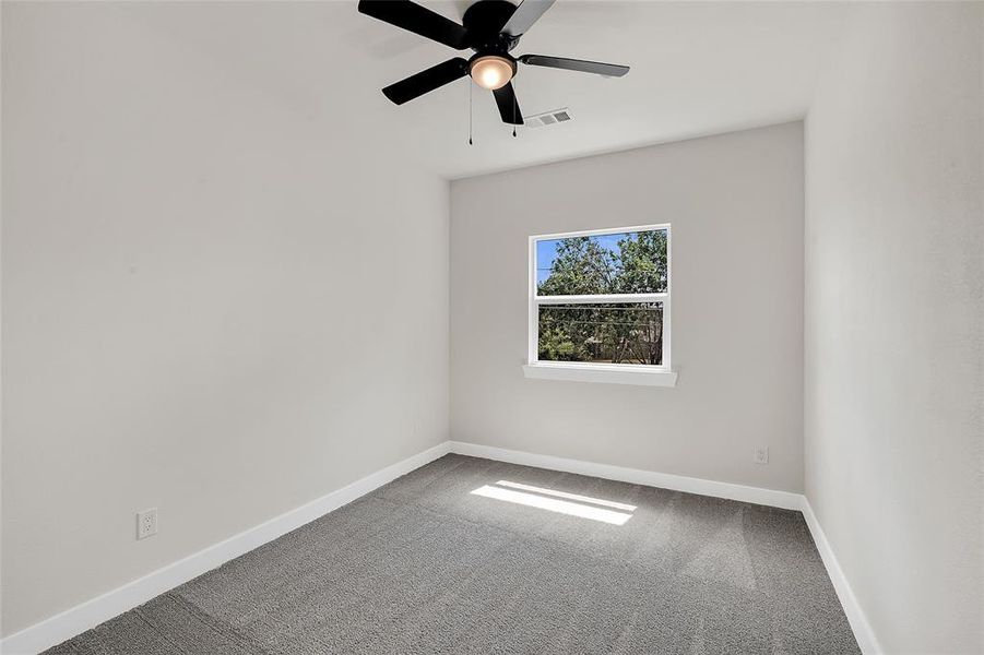 Carpeted empty room featuring ceiling fan