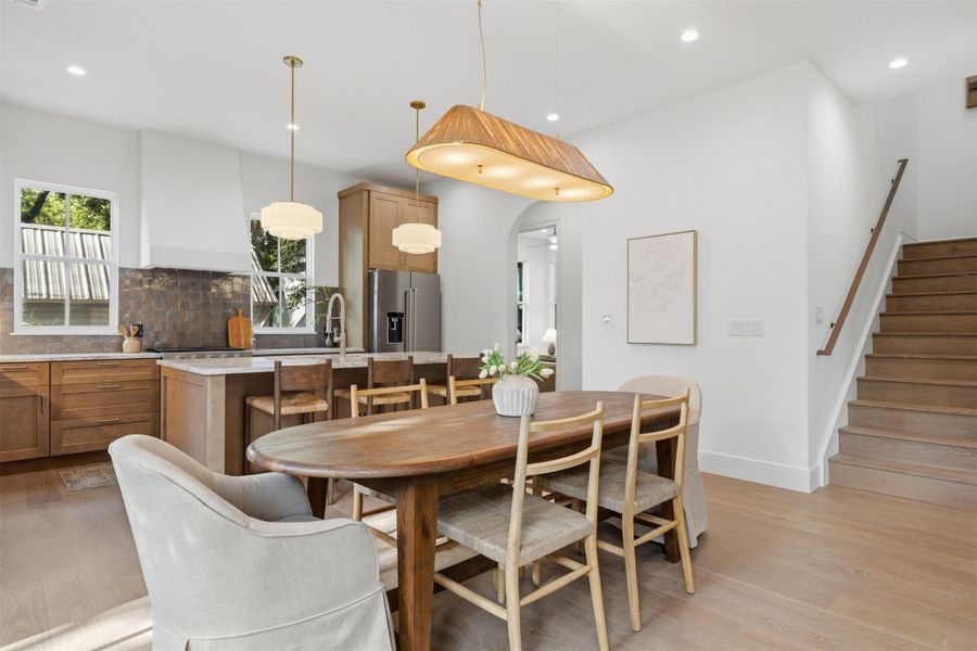 An inviting open-concept kitchen and dining area features abundant natural light and rich wood flooring.
