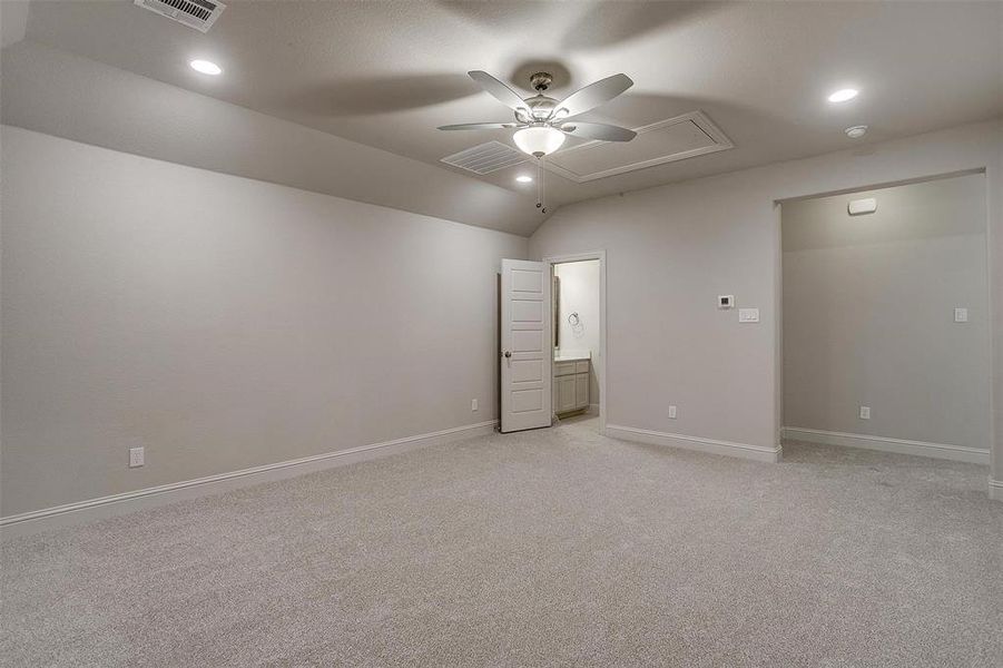 Unfurnished bedroom with ceiling fan, light colored carpet, ensuite bathroom, and lofted ceiling