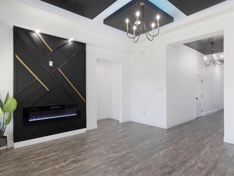 Unfurnished living room featuring dark wood-type flooring and a notable chandelier