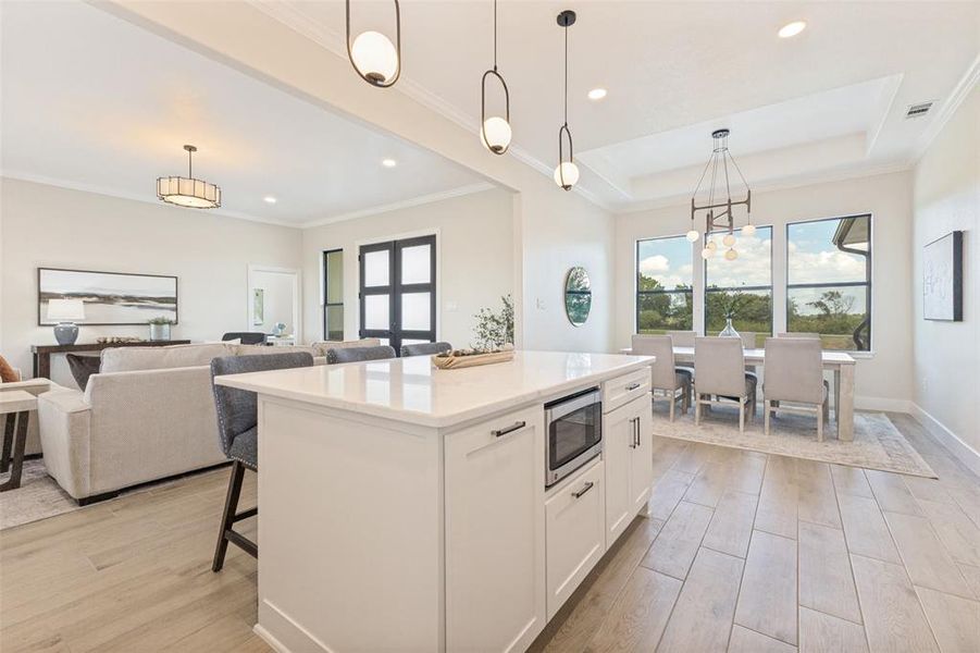 Kitchen island with quartz countertop, integrated microwave, and pendant lighting