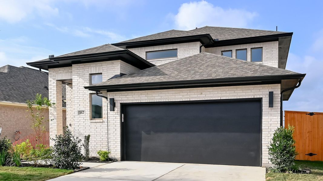 View of front of property with a shingled roof, a garage, concrete driveway, and brick siding View of front of property with a shingled roof, a garage, concrete driveway, and brick siding