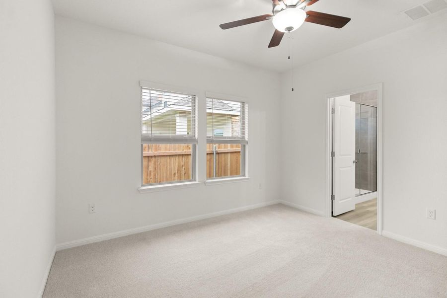 This room features light-colored carpeting, a ceiling fan with integrated lighting, and two windows with blinds