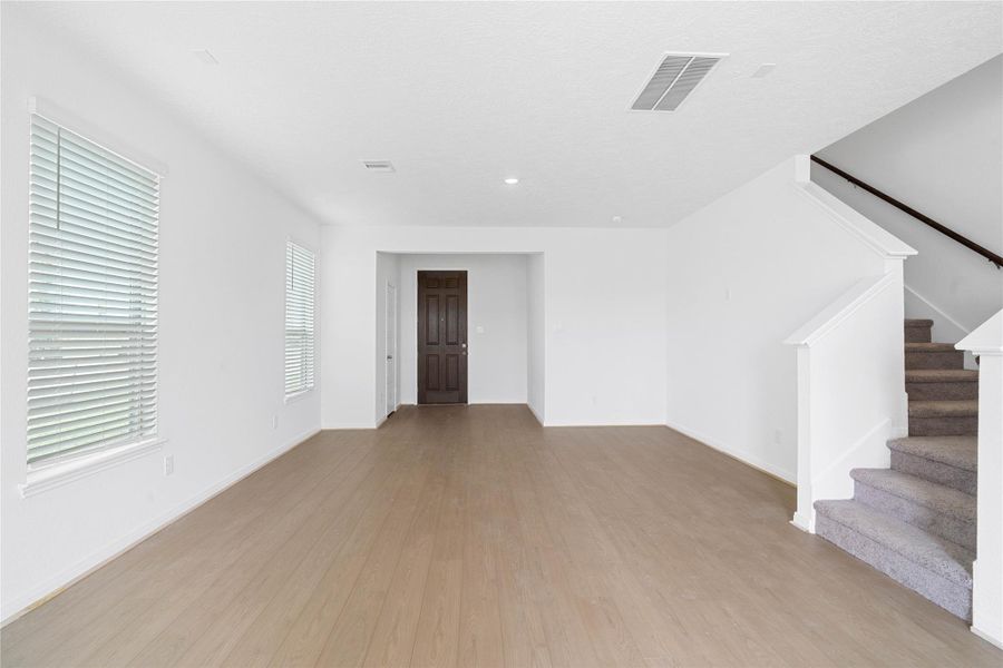 Bring family and friends together in this beautiful family room! It features high ceilings, recessed lighting, custom paint, stunning Bandera vinyl plank flooring in Toasted Sienna, and large windows that fill the space with natural light all day long.