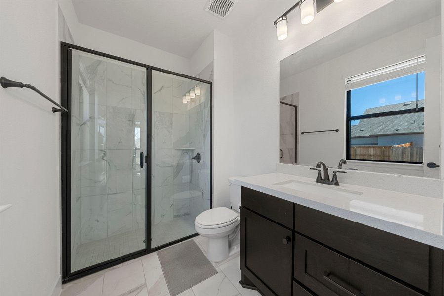 Full bath featuring a marble finish shower, visible vents, toilet, marble finish floor, and vanity