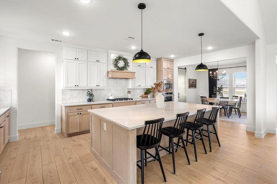 Kitchen with pendant lighting, stainless steel appliances, a large island, and a notable chandelier