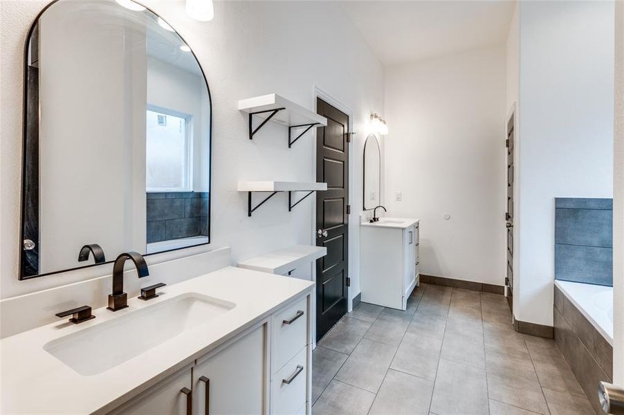 Bathroom with tile patterned flooring, vanity, and tiled bath