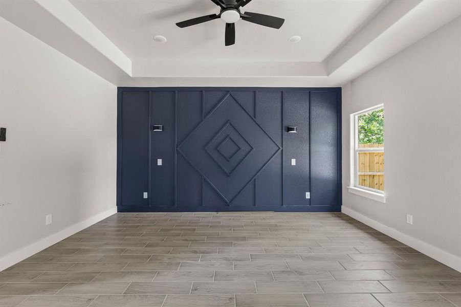 Unfurnished bedroom with wood tiled floors, baseboards, a ceiling fan, and a tray ceiling