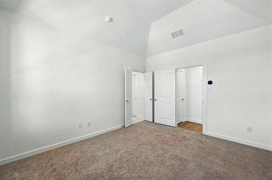 Unfurnished bedroom featuring carpet flooring and high vaulted ceiling