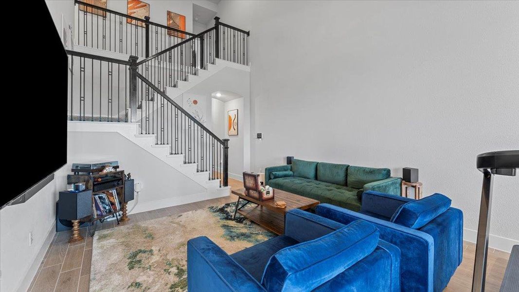 Living area with wood finish floors, a high ceiling, and stairs Living area with wood finish floors, a high ceiling, and stairs