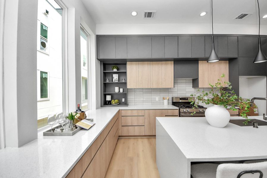 Bright kitchen with expansive windows, quartz countertops, open display shelving, and stainless steel appliances.