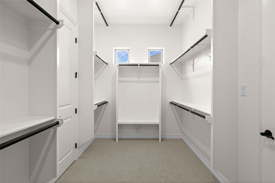 Walk-in closet offering ample storage with shelving, hanging rods, and twin elevated windows. Walk-in closet offering ample storage with shelving, hanging rods, and twin elevated windows.