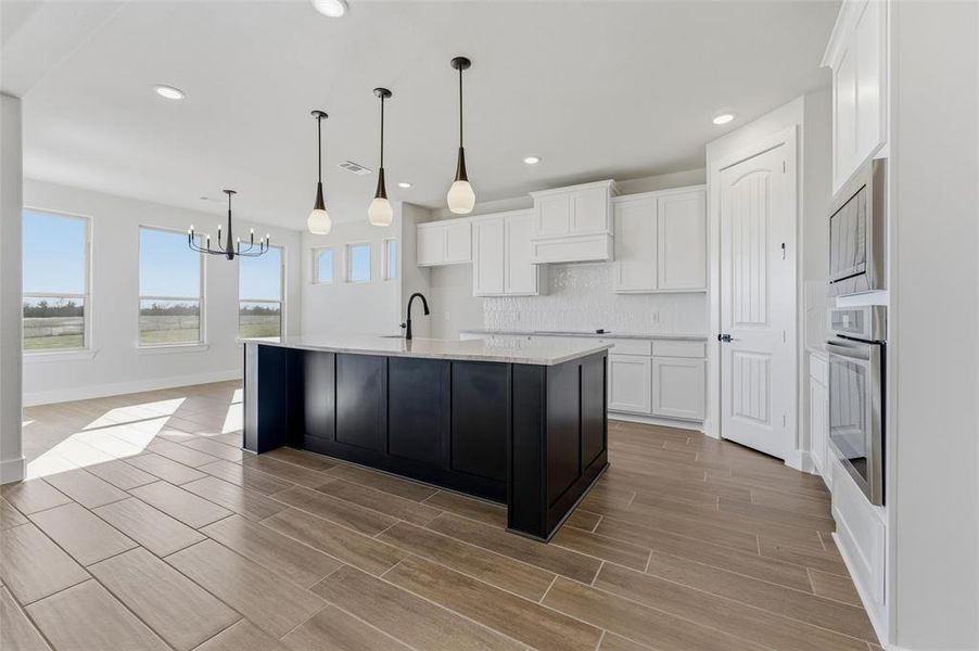 Kitchen with white cabinetry, backsplash, wood finish floors, dark cabinetry, and recessed lighting