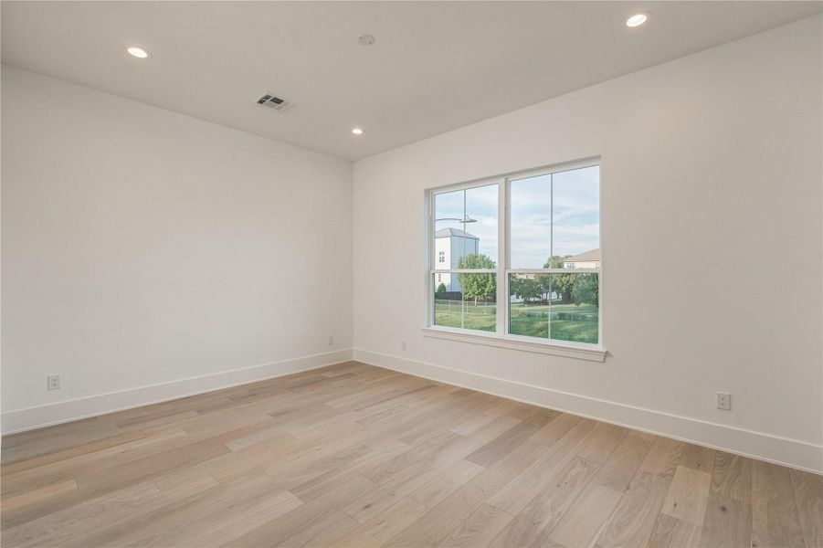 A generously proportioned secondary bedroom offers flexibility for a variety of layouts, with a wide window bringing in natural light and views toward the backyard.