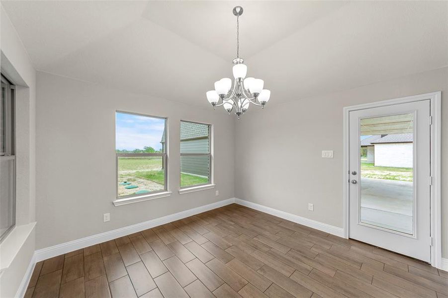 Open-concept room featuring wood-finish tile flooring, multiple windows, and a glass-paneled exterior door
