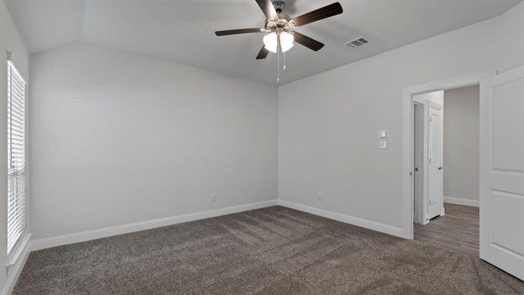 Carpeted empty room with ceiling fan and vaulted ceiling