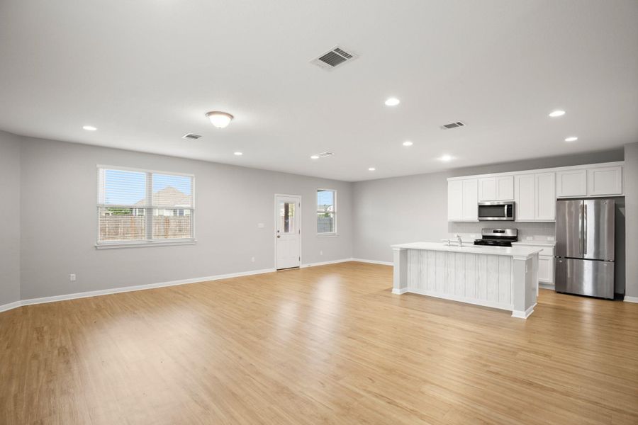 Kitchen with appliances with stainless steel finishes, open floor plan, light wood-style floors, white cabinets, and recessed lighting