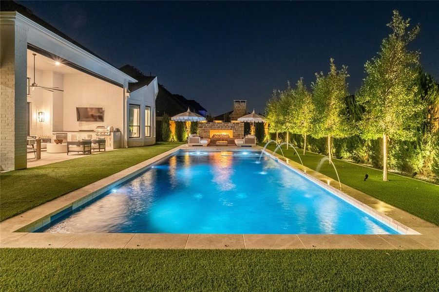 View of pool featuring pool water feature, a patio, a lawn, and exterior kitchen