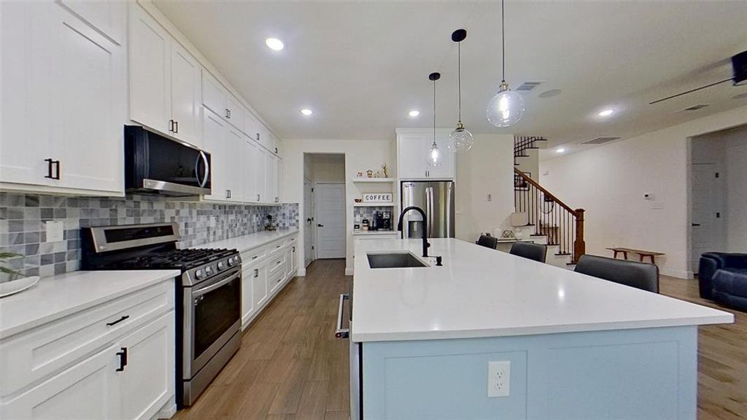Kitchen featuring appliances with stainless steel finishes, white cabinetry, pendant lighting, tasteful backsplash, and recessed lighting