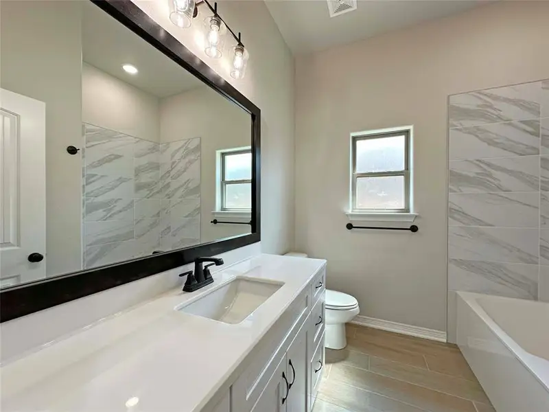 Bathroom with vanity, plenty of natural light, wood tiled floors, and shower / tub combination Bathroom with vanity, plenty of natural light, wood tiled floors, and shower / tub combination