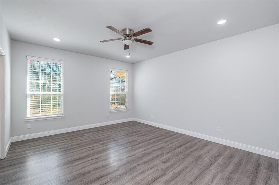 Unfurnished room featuring plenty of natural light, baseboards, and wood finished floors