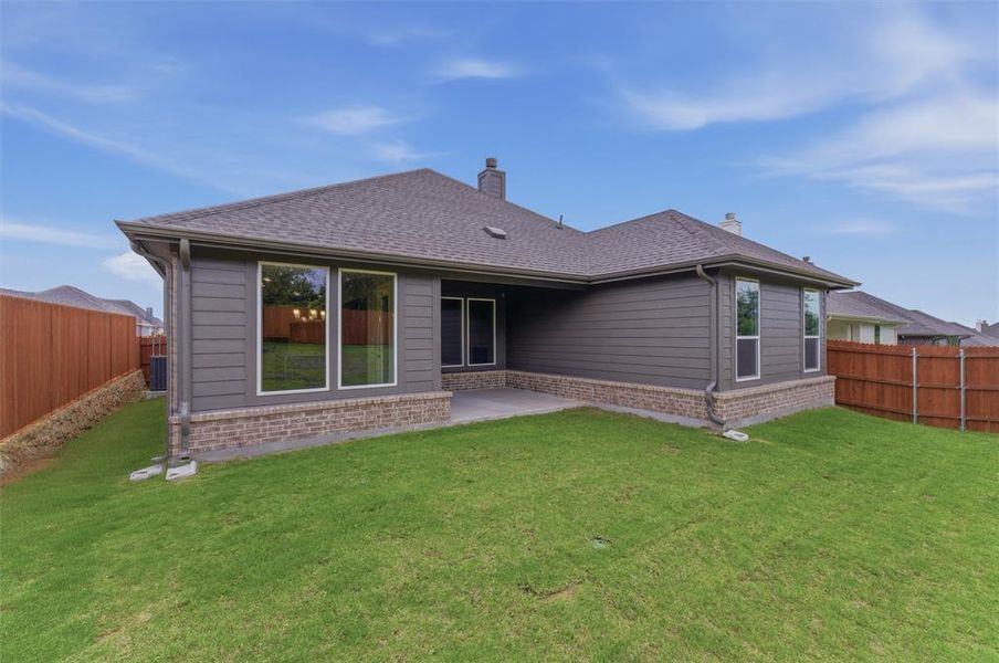 Rear exterior featuring a covered patio, brick and siding facade, and multiple windows