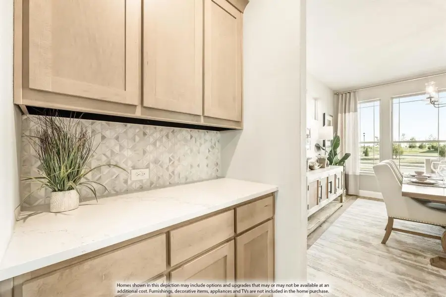 Kitchen butler's pantry with light wood cabinets, white quartz countertop, and geometric tile backsplash, opening to dining room.