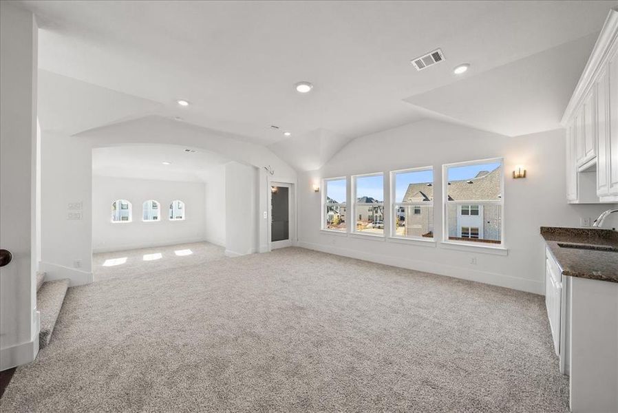 Game room and media room featuring lofted ceilings, natural light, carpet, and a wet bar Game room and media room featuring lofted ceilings, natural light, carpet, and a wet bar