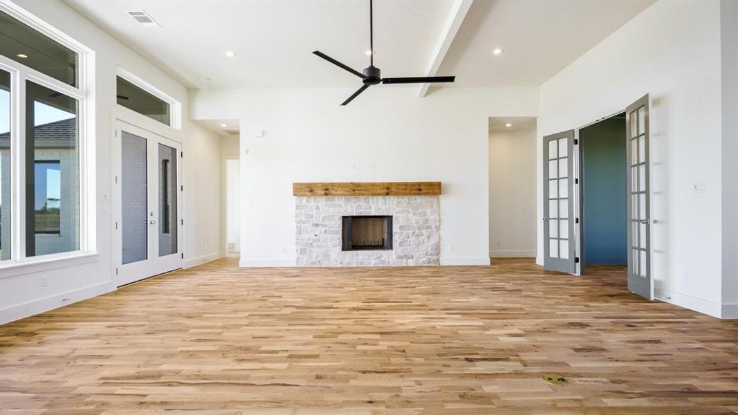 Unfurnished living room with light hardwood / wood-style flooring, french doors, a fireplace, and ceiling fan