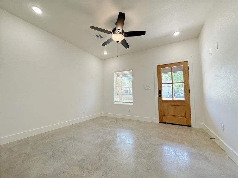 Empty room with visible vents, baseboards, a ceiling fan, and finished concrete floors Empty room with visible vents, baseboards, a ceiling fan, and finished concrete floors