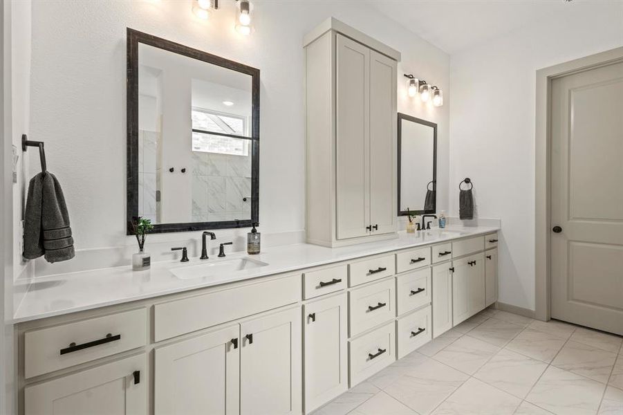 Bathroom with double vanity, marble look tile flooring, and a marble finish shower