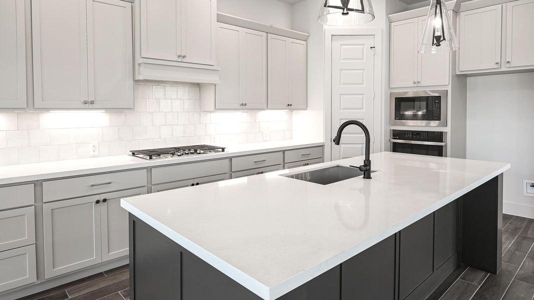 Kitchen with wood tiled floors, dark cabinetry, and tasteful backsplash